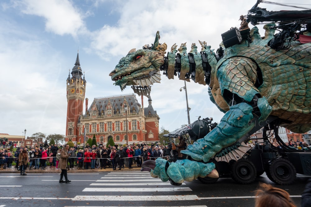 Le Dragon de Calais crossing the street in front of the Hôtel de Ville and its belfry, Calais, France
