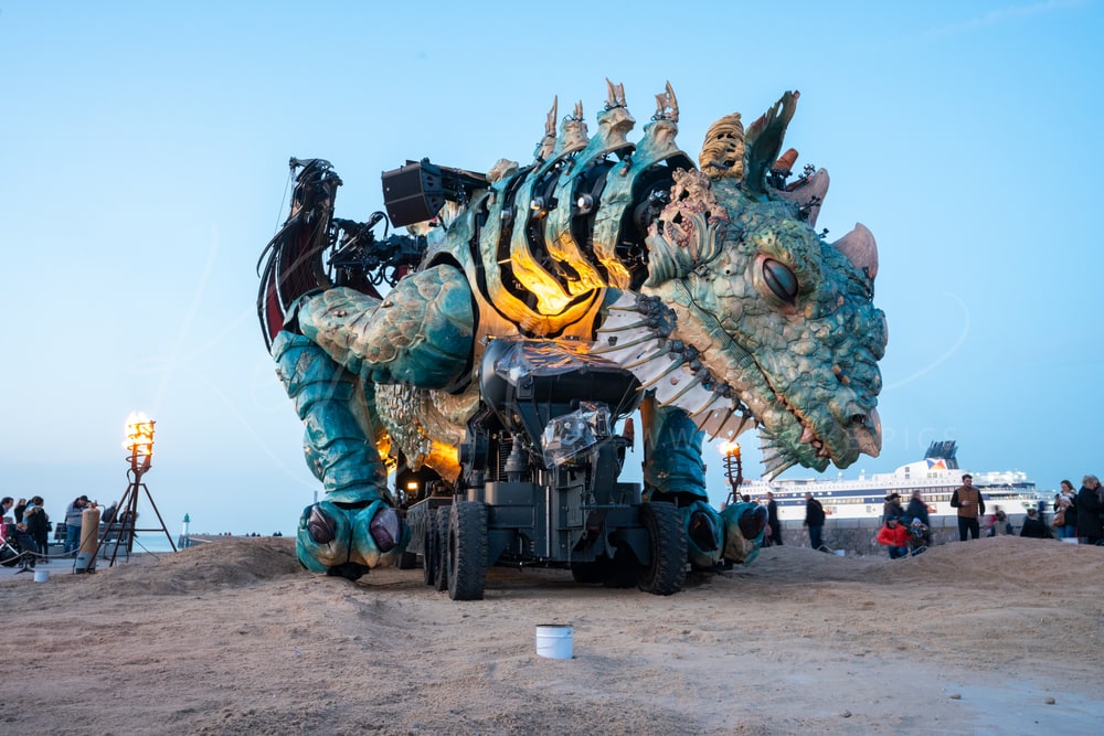 Le Dragon de Calais, a giant mechanical dragon, on the beach at dusk with a ferry behind, Calais, France